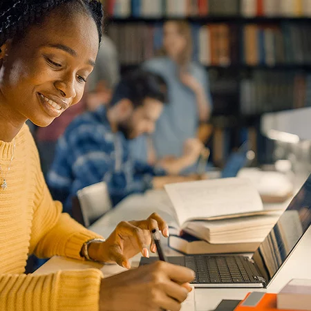 University student studying with a laptop and books